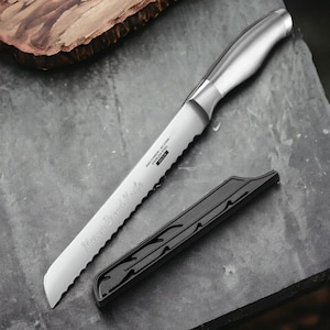 May include: A silver bread knife with a serrated edge and a black plastic sheath. The knife has the words "Mango Bread Knife" engraved on the blade and "High Carbon - No Stain - Stainless Steel" printed on the side.