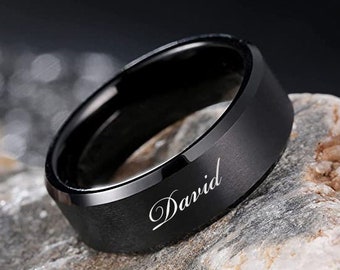 May include: A black ring with a beveled edge and the name "David" engraved in white lettering.