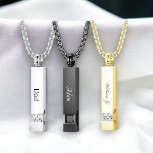 Può includere: Tre collane in argento, nero e oro con ciondoli rettangolari. Ogni ciondolo ha un nome diverso inciso su di esso: "Dad", "Adan" e "William G". Ogni ciondolo ha una piccola fila di pietre di zircone cubico trasparenti.