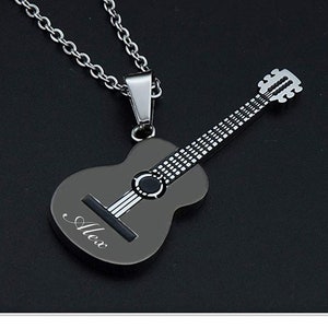 May include: A silver chain necklace with a black guitar pendant. The guitar has a silver string design and the name "Alex" is engraved on the body.