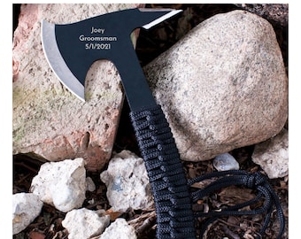 May include: Black axe with a black paracord handle and a silver blade. The axe has the text "Joey Groomsman 5/1/2021" engraved on the blade.