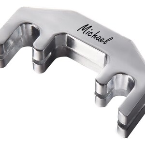 May include: Silver-toned violin tuning peg holder with the word "Michael" engraved on the top.