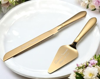 May include: Gold cake knife and server set with the names "David & Samantha" and the date "March 11, 2023" engraved on them. The set is on a white plate.