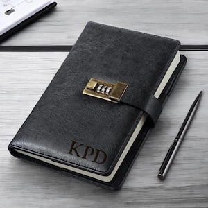 May include: Black leather journal with a combination lock and the initials "KPD" engraved on the front.