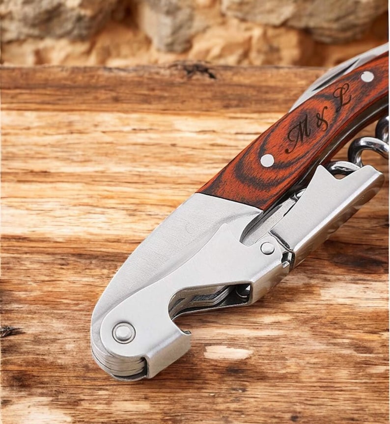 May include: A silver and wood wine opener with a wooden handle engraved with "M & L".