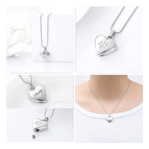 May include: Silver heart-shaped cremation necklace with a paw print design. The necklace is shown on a white background and on a model wearing the necklace. The pendant has a small opening on the side for ashes or other mementos. The necklace is engraved with the name "Dusty".