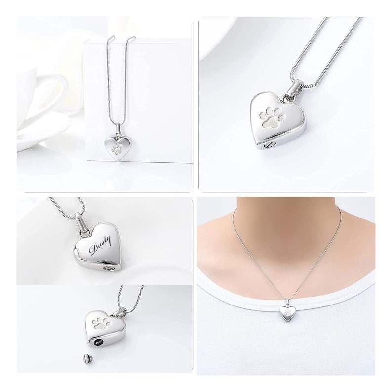 May include: Silver heart-shaped cremation necklace with a paw print design. The necklace is shown on a white background and on a model wearing the necklace. The pendant has a small opening on the side for ashes or other mementos. The necklace is engraved with the name "Dusty".