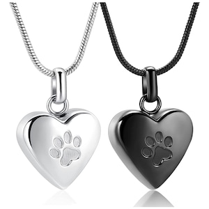 May include: Two heart-shaped cremation pendants with paw print designs. One pendant is silver and the other is black. Both pendants are on silver and black chains.