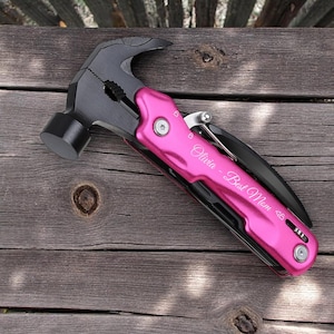 May include: A pink multi-tool with a hammer head, pliers, and a knife. The tool is engraved with the text "Olivia - Best Mom 4B".