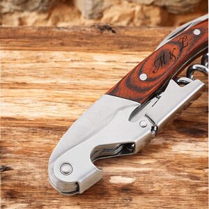 Pu&ograve; includere: Un apribottiglie in argento e legno con un manico in legno inciso con "M & L".