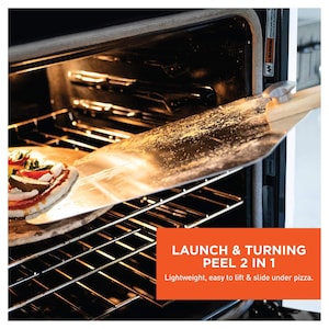 May include: A pizza peel being used to remove a pizza from an oven. The peel is made of metal and wood. The text on the image says "LAUNCH & TURNING PEEL 2 IN 1". The pizza has tomato sauce, cheese, and vegetables.