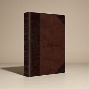 May include: A brown leather-bound Bible with the name "Michael" embossed on the cover. The spine features the words "Holy Bible" and other text. The book has a two-tone design with darker brown accents.