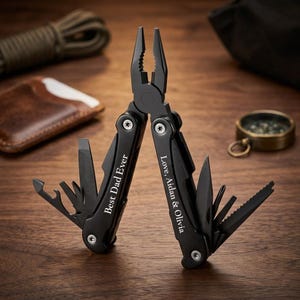 May include: Black multi-tool with pliers, a knife, and other tools. The text "Best Dad Ever" is engraved on the handle. The text "Love, Aidan & Olivia" is also engraved on the handle. The tool is open, displaying its various functions.