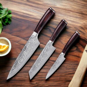May include: Set of three kitchen knives with brown wooden handles. The blades are engraved with the text "Chef David".
