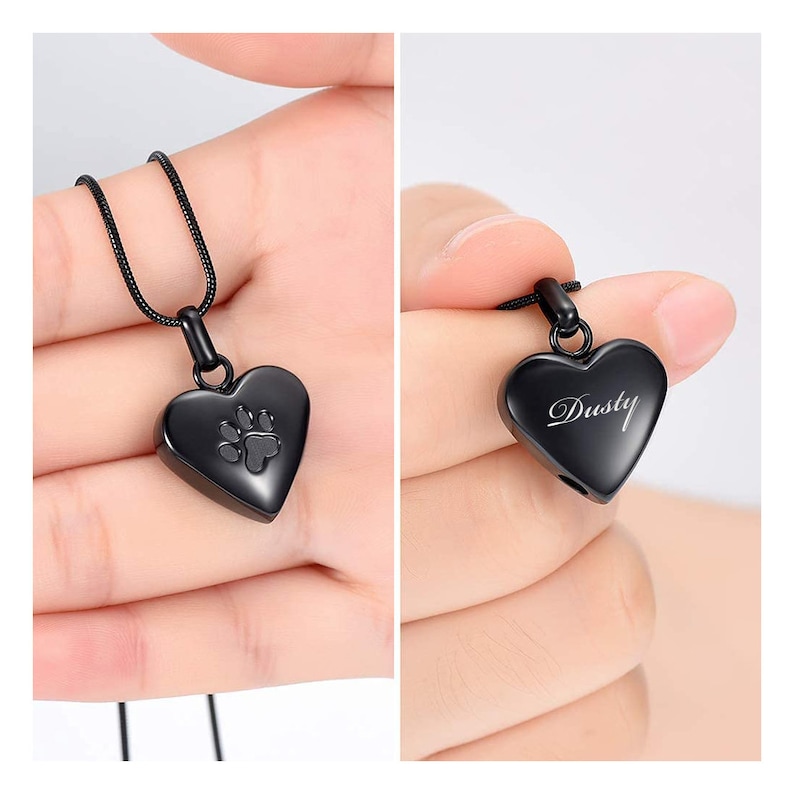 May include: Black heart-shaped pendant necklace with a paw print engraved on the front. The back of the pendant is engraved with the name "Dusty".