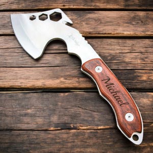 Op de afbeelding: Een gepersonaliseerde bijl met een houten handvat en een metalen kop. Het handvat is gegraveerd met de naam "Michael".