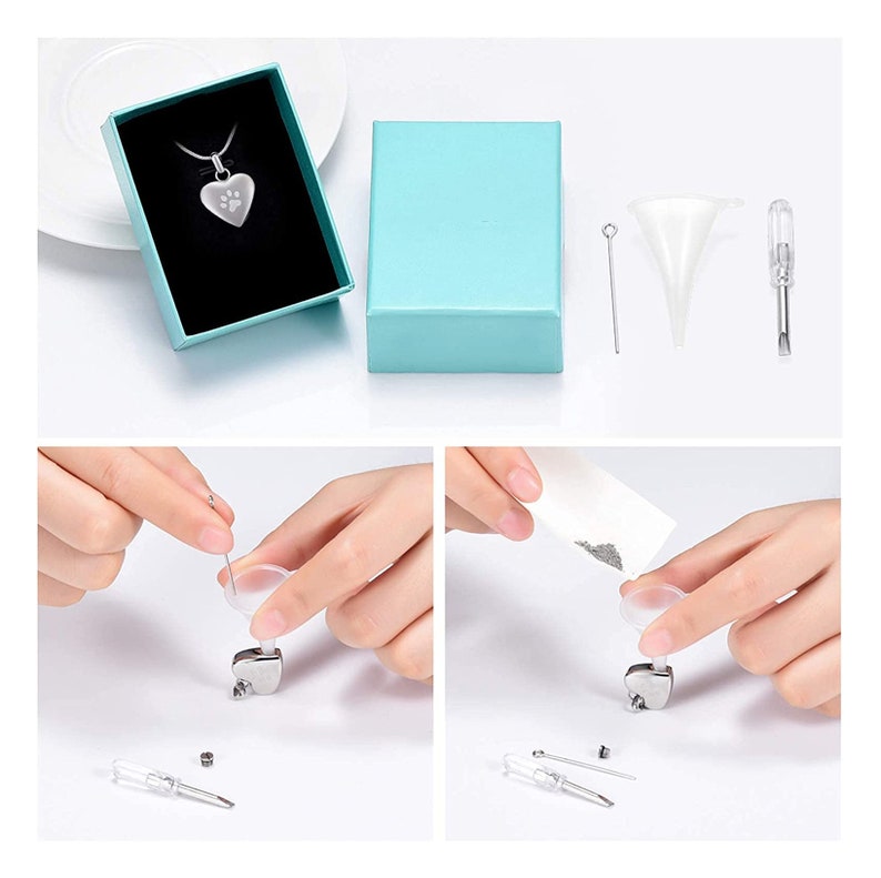 May include: A silver heart-shaped cremation necklace with a paw print design. The necklace comes with a small funnel, a screwdriver, and a pin for filling the pendant with ashes. The necklace is packaged in a light blue box.