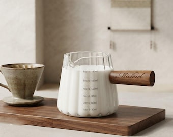 May include: A clear glass pitcher with a fluted design and a wooden handle engraved with the name Michael. The pitcher features printed measurement markings from 1oz to 6oz and 30ml to 180ml, accompanied by a speckled ceramic coffee dripper.