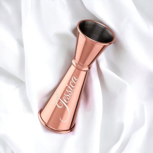 May include: Rose gold cocktail jigger with a personalised inscription that reads "Jessica". The jigger has measurements in ounces and millilitres.