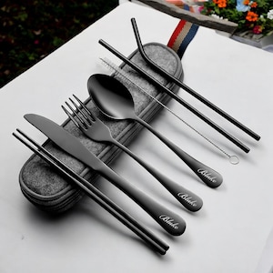 May include: A black reusable cutlery set with a knife, fork, spoon, chopsticks, and two straws. The set comes with a gray felt carrying case and is engraved with the word "Blake".