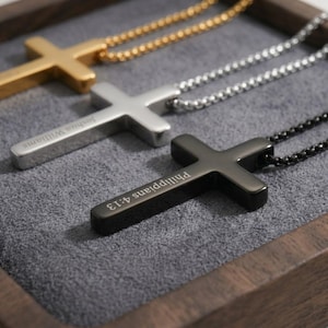 May include: Three cross pendants on matching metal chains. The gold-tone cross is plain, the silver-tone cross is engraved with the name Joshua Williams, and the black cross is engraved with the text Philippians 4:13 on the vertical bar.