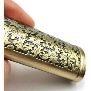 Puede incluir: Un encendedor de color dorado con un intrincado dise&ntilde;o floral grabado en la superficie. El encendedor tiene una forma redondeada y un acabado liso.