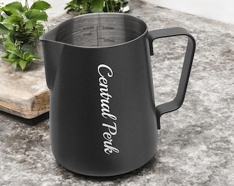 May include: Black stainless steel pitcher with a black handle. The pitcher has measurements in ounces and milliliters. The text "Central Perk" is printed on the side of the pitcher.
