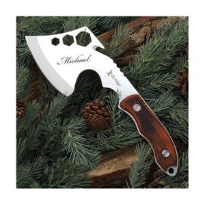 Op de afbeelding: Een zilveren bijl met een bruine houten steel. De bijl heeft een multitool-kop met een moersleutel, een flesopener en andere gereedschappen. De bijl is gegraveerd met de tekst "Michael" en "Elk Ridge".
