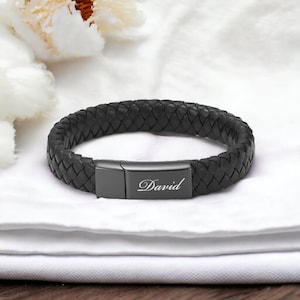 May include: Black leather bracelet with a black metal clasp engraved with the name "David".