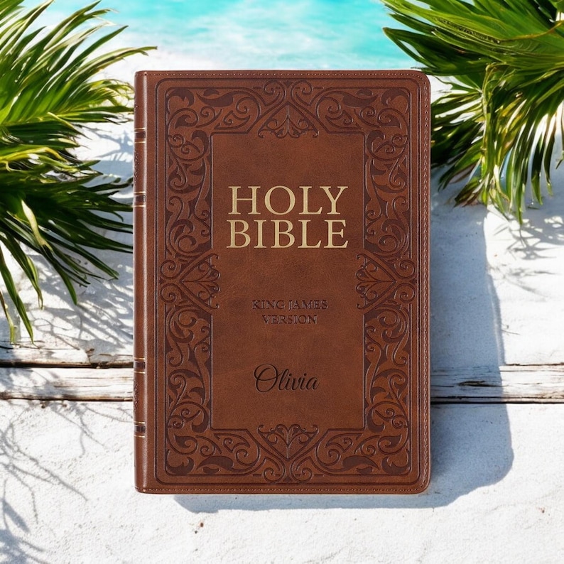 May include: A brown leather-bound Holy Bible with gold lettering and an ornate design. The Bible is personalised with the name "Olivia" and features the King James Version.