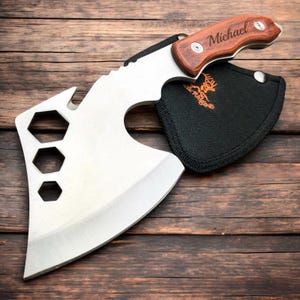 Op de afbeelding: Een gepersonaliseerde bijl met een houten handvat en een zwarte schede. Het handvat is gegraveerd met de naam "Michael".