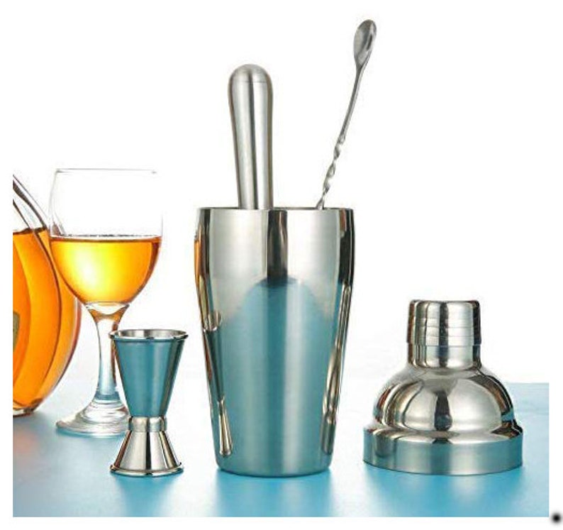 Op de afbeelding: Een set van roestvrijstalen cocktailshaker, jigger en roerstaaf. De shaker heeft een deksel en een ingebouwde muddler. De jigger is een dubbelzijdige maatbeker. De roerstaaf heeft een gedraaide handgreep.