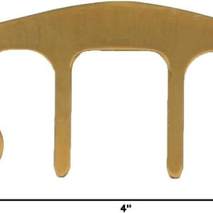 May include: A gold-colored metal wire cable clip with three prongs, measuring 4 inches wide and 2 inches tall.