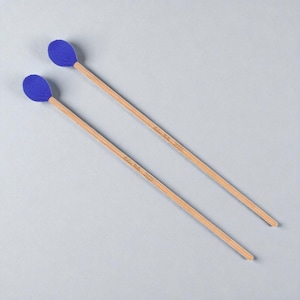 May include: Two blue-headed percussion mallets with wooden handles, angled on a light gray surface. The text "Adam Miller 2025" is printed on each handle. The mallets are designed for musical instruments.