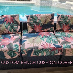 May include: A set of three custom bench cushion covers featuring a tropical leaf print in shades of green, pink and red. The covers have a large leaf design on a pink background. The text "CUSTOM BENCH CUSHION COVER" is printed at the bottom of the image.