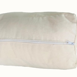 May include: A rectangular, off-white pillow with a white zipper closure. The pillow is made of a soft, textured fabric. The zipper runs along one side of the pillow, allowing for easy removal of the pillow's contents.