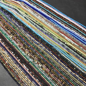 Puede incluir: Una colección de cuentas de piedras preciosas de varios colores, dispuestas en filas sobre una superficie negra. Las cuentas son pequeñas y redondas, y están hechas de diferentes tipos de piedras preciosas, como amatista, turquesa y jaspe.