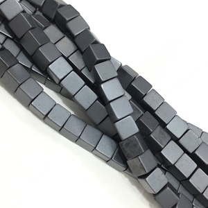 Peut inclure: Un brin de perles carrées de couleur gris foncé en hématite.