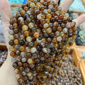 May include: A strand of brown, white, and orange agate beads. The beads are round and have a natural, polished finish.
