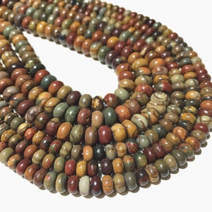 May include: A collection of gemstone beads in earthy tones of brown, green, and red. The cylindrical beads are strung together, suitable for a necklace or bracelet. The beads are approximately 1.3 cm in diameter.