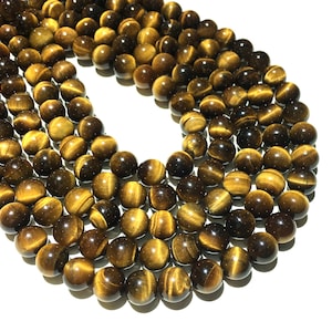 May include: A strand of round, golden brown tiger's eye beads. The beads have a shimmering, chatoyant effect.