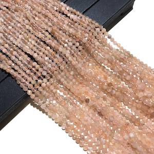 May include: A strand of round, faceted, peach-colored sunstone beads. The beads are approximately 4mm in diameter and have a natural, slightly irregular shape.