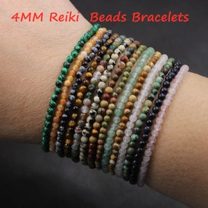 Puede incluir: Una pila de pulseras de cuentas Reiki de 4 mm en varios colores y patrones, incluyendo verde, marrón, negro, blanco y azul.