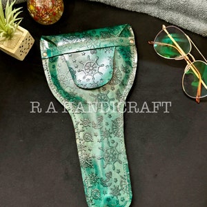 Puede incluir: Un estuche para gafas de cuero verde con tem&aacute;tica n&aacute;utica. El estuche est&aacute; decorado con anclas, estrellas y timones de barco. El estuche tiene una solapa con cierre de presi&oacute;n.