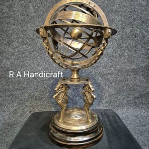 Könnte beinhalten: Ein himmlischer Globus aus Messing auf einem Ständer mit einem Kompass. Der Globus ist mit Sternbildern und Tierkreiszeichen verziert. Der Ständer ist mit verzierten Tierfiguren geschmückt.