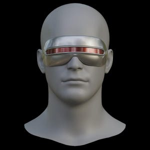 Może przedstawiać: Srebrna osłona z czerwoną soczewką, spoczywająca na szarej głowie manekina. Osłona ma elegancki, futurystyczny design, z zakrzywioną górą i prostokątną soczewką. Tło jest czarne.