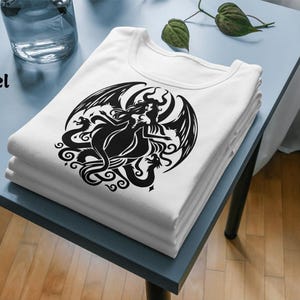 May include: A white t-shirt with a black iron-on design of two women with wings and a dragon. The text "Iron on apparel" is visible in the top left corner of the image.