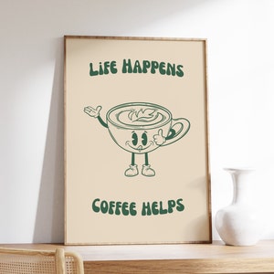 K&ouml;nnte beinhalten: Ein gerahmter Kunstdruck mit dem Text "LIFE HAPPENS COFFEE HELPS" in Dunkelgr&uuml;n. Das Kunstwerk zeigt eine Cartoon-Kaffeetasse mit einem l&auml;chelnden Gesicht, Armen und Beinen. Der Hintergrund ist hellbeige.