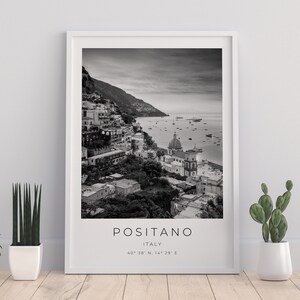 May include: Black and white photograph of Positano, Italy. The image shows a hillside town with colorful buildings, a church, and a view of the Mediterranean Sea. The text "Positano, Italy" and the coordinates "40&deg; 38' N, 14&deg; 29' E" are printed below the image.