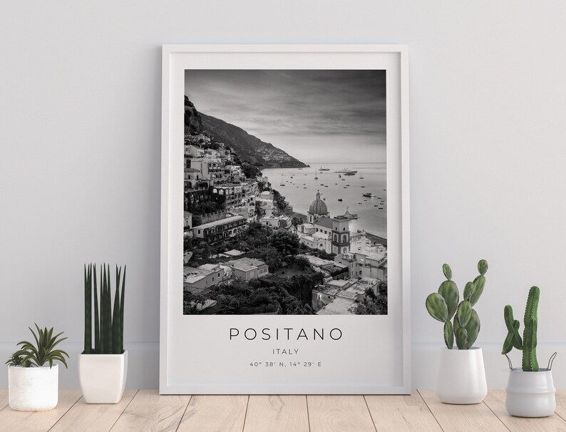 May include: Black and white photograph of Positano, Italy. The image shows a hillside town with colorful buildings, a church, and a view of the Mediterranean Sea. The text "Positano, Italy" and the coordinates "40&deg; 38' N, 14&deg; 29' E" are printed below the image.